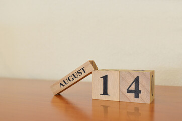 August 14, Date design with calendar cube on wooden table and white background.