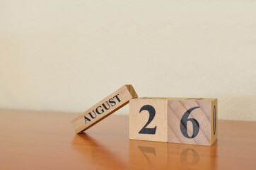 August 26, Date design with calendar cube on wooden table and white background.