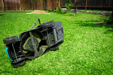 Close-up of an inverted electric lawn mower. Mowing grass, lawn, paths. Lawn mower bottom