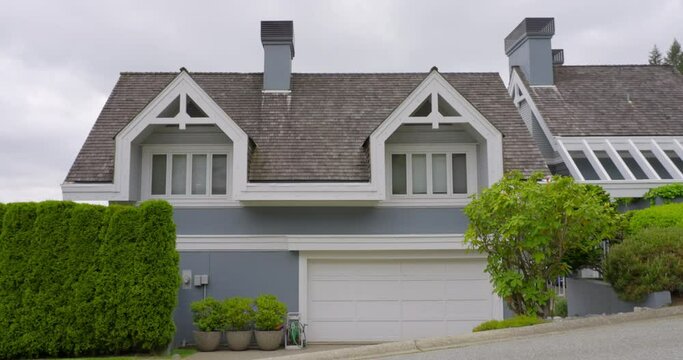 Establishing shot of two story stucco luxury house with garage door, big tree and nice landscape in Vancouver, Canada, North America. Day time on May 2021. ProRes 422 HQ.