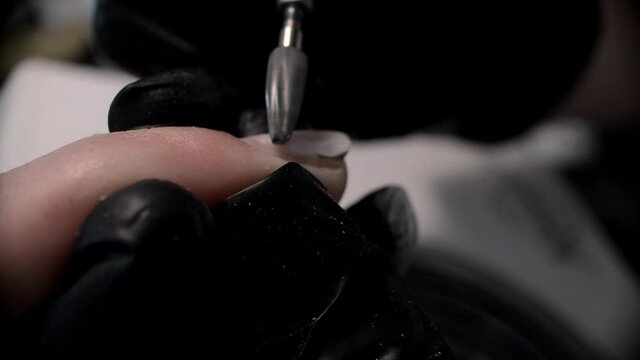 close-up manicurist removes the old coating on the nail plate wearing black gloves. Self care authentic. The concept of beauty professional nail care