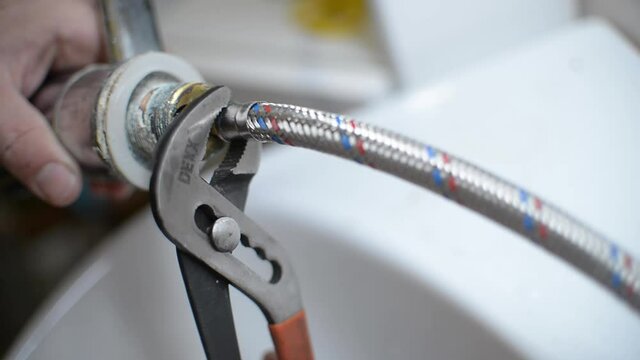 HOUSEHOLD CHORES. MAN CHANGES RUSTY LIME BATHROOM MIXER WITH OWN HANDS diy plumber conceptual. tightens new replacement hoses with a spanner