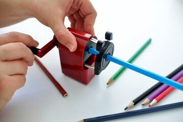 hand holds Mechanical pencil sharpener with colored pencils on white background. back to school. preparing for school stationery for study.