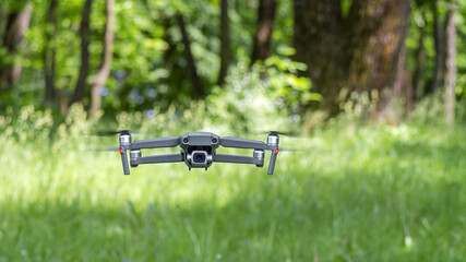 drone flying in forest against blurred green trees background. sunny summer day.