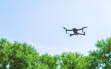 quadcopter on takeoff against green trees and blue sky. closeup view