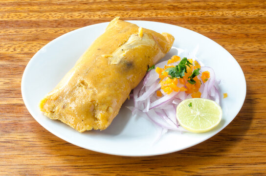Peruvian tamale, traditionally eaten for breakfast on Sundays, made of corn and chicken and served with salsa criolla - onion salad.