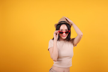 Beautiful young south east Asian woman red frame sunglass hat pose fashion peak happy on yellow orange background