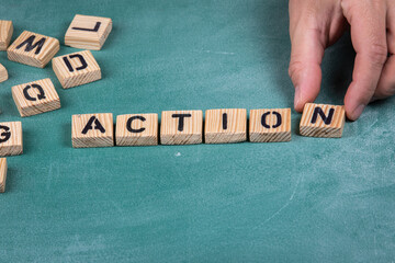 Action. Wooden alphabet letters on a green blackboard background