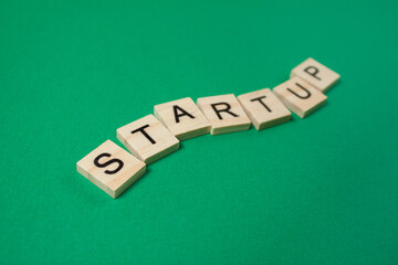 Word Startup made of wooden letters on a green background