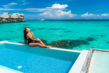 Luxury resort vacation travel woman sunbathing by overwater bungalow swimming pool in Bora Bora,...