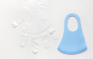 Set with protective blue face mask and  disposable vinyl gloves above white background with copy space. Infection prevention during lockdown.