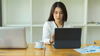 Female worker using digital tablet on wooden table in working space
