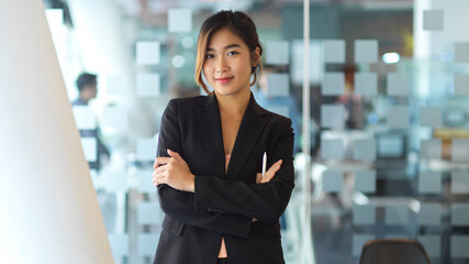 Half-length portrait of businesswoman in black suit smiling to camera