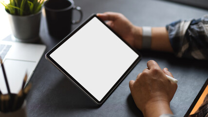 Businessman using digital tablet with mock-up screen on dark working space
