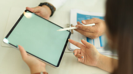 Side view of two people hands using digital tablet on white table