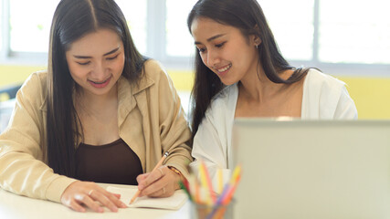 Portraits of two female students talking to each other about their group assignment