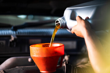 Old car oil change mechanic. Add new oil to the car. Pour fresh oil at the service station.