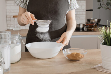 The process of making gluten-free baked goods.  Rice flour is sieved through a sieve. Concept of vegan treats.