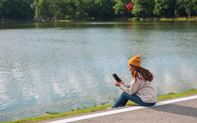 A young woman holding and using digital tablet while traveling mountains and lake