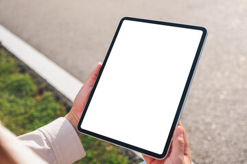 Mockup image of a woman holding digital tablet with blank white desktop screen in the outdoors