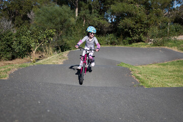 young caucasian girl riding push bike on pump track helmet fit outdoors active fun learn exercise...