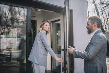 Woman entering office and man opening door