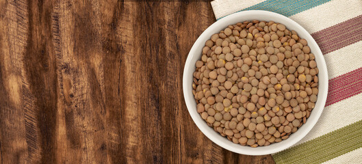 Walnut wood textureLentils in a Ceramic Bowl. These nutritious legumes are high in protein and fiber. The image is a cut out, isolated on a white background, with a clipping path.