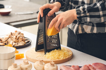 Woman grating cheese in kitchen