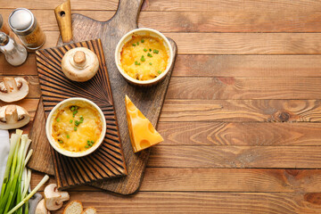 Ramekins with tasty julienne and ingredients on wooden background