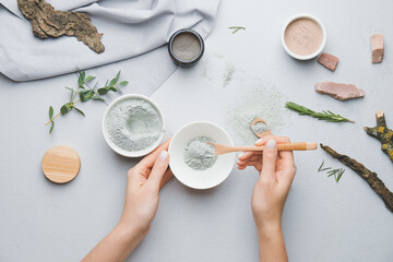 Woman preparing facial mask on grey background