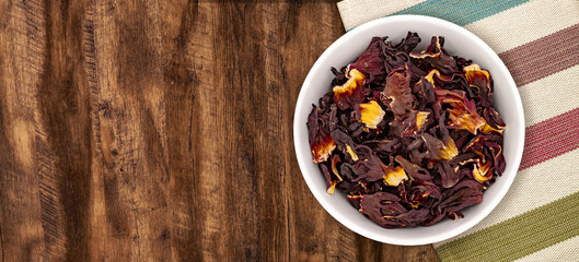 Walnut wood textureDry Organic Jamaica Flower Hibiscus for Tea. Top view of bowl with Jamaica Flower Hibiscus. Detailed view of hibiscus tea on wooden background