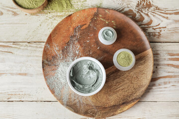 Plate with different cosmetic clay on light wooden background