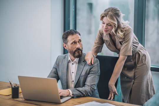 Man behind laptop woman touching his shoulder