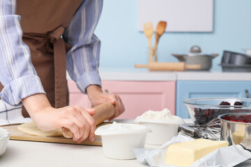 Obraz na płótnie Canvas Woman making dough on board in kitchen