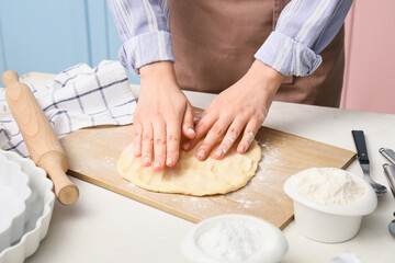 Woman kneading dough on board in kitchen