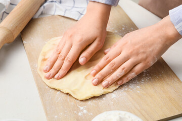 Fototapeta premium Woman kneading dough on board in kitchen, closeup