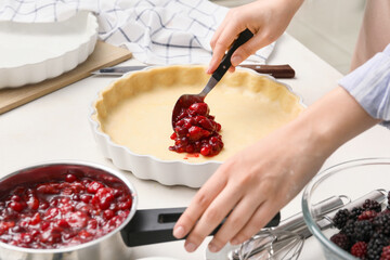 Woman cooking berry pie in kitchen