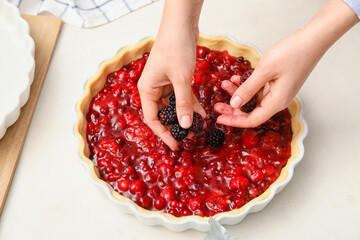 Woman cooking berry pie in kitchen
