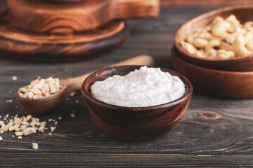 Bowl of sour cream with cashew nuts on dark wooden background