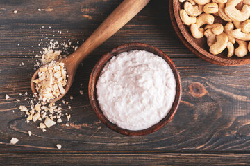 Bowl of sour cream with cashew nuts on dark wooden background