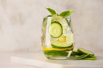 Glass with cucumber lemonade on light background