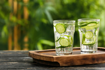 Glasses of cucumber lemonade on table outdoors