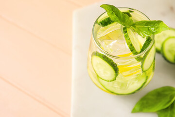 Glass with cucumber lemonade on color wooden background