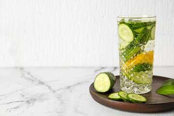 Glass with cucumber lemonade on light background