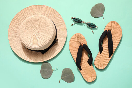 Stylish beach hat with sunglasses and flip-flops on color background
