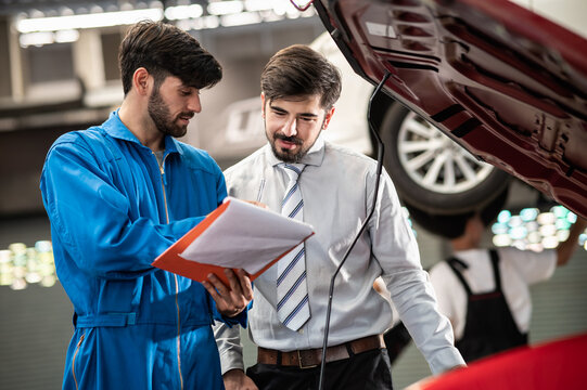 Car service, vehicle repair concept : Car service technician explaining checking list or repaired item to vehicle owner customer after sending car for repairing or check at automobile service center.