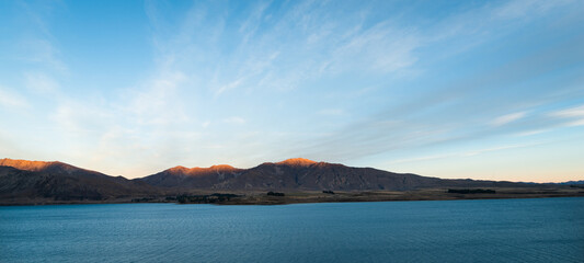 Lake Tekapo at sunset. Setting sun lit up top of the mountains. South Island