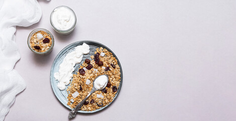 Granola with chia seeds, coconut, dry berries and yogurt in bowls on grey background, copy space. Concept of healthy breakfast menu 