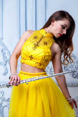 Portrait young woman model in stage yellow dress with flute