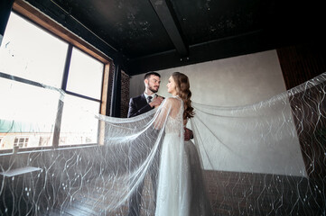 beautiful wedding couple. bride with a long white veil and in a wedding dress. groom in a stylish...